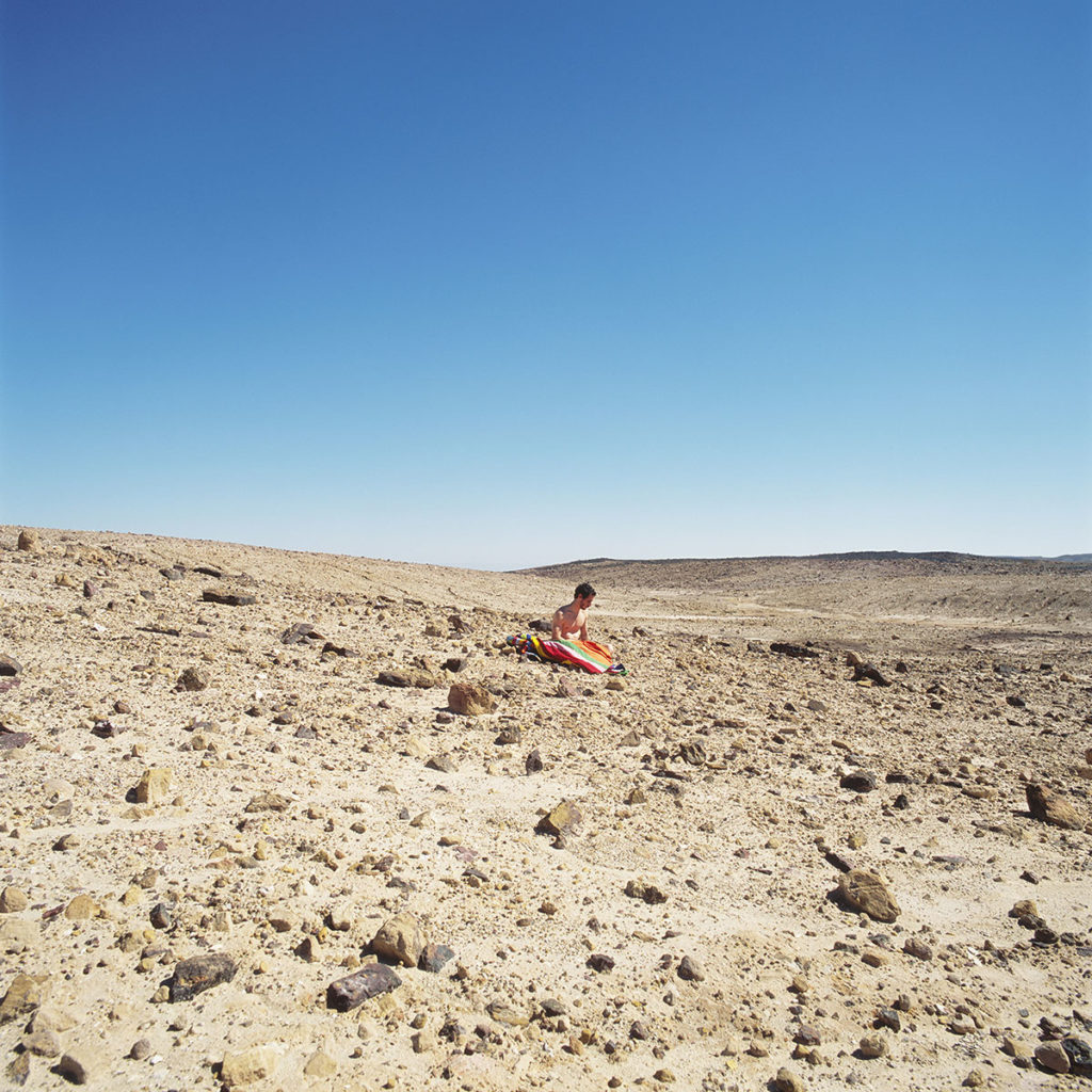 Mann alleine in der Wüste sitzend
